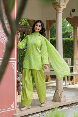 A woman models a bright lime green traditional Indian outfit consisting of a kurta with diagonal stripes, wide-leg pants, and a matching dupatta, set against an outdoor architectural background with pillars.