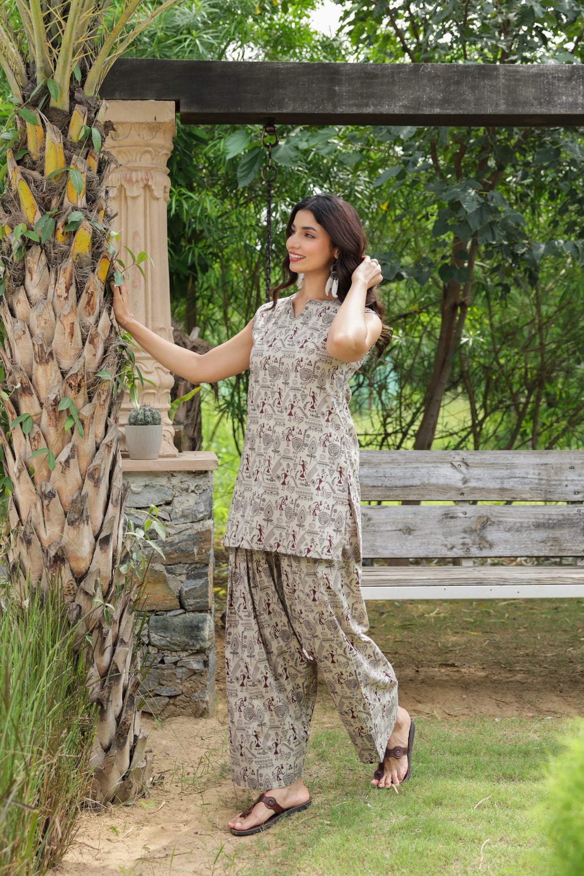 Aarika beige folk print cotton Farshi Salwar Set with sleeveless kurta and matching printed Farshi salwar, styled outdoors in a garden setting.
